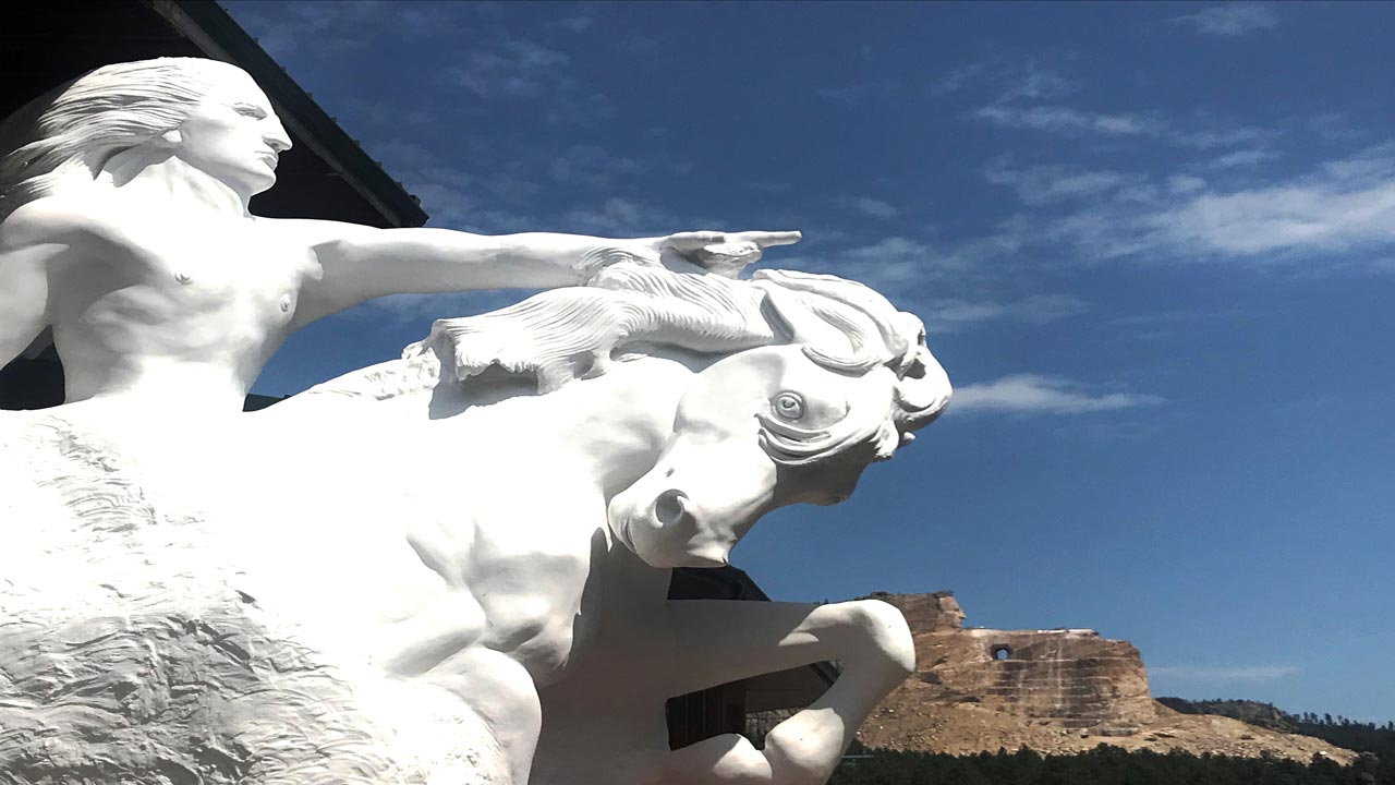 Up close view of Crazy Horse Statue, in summertime, in front of monument in the distance within the Black Hills of South Dakota.