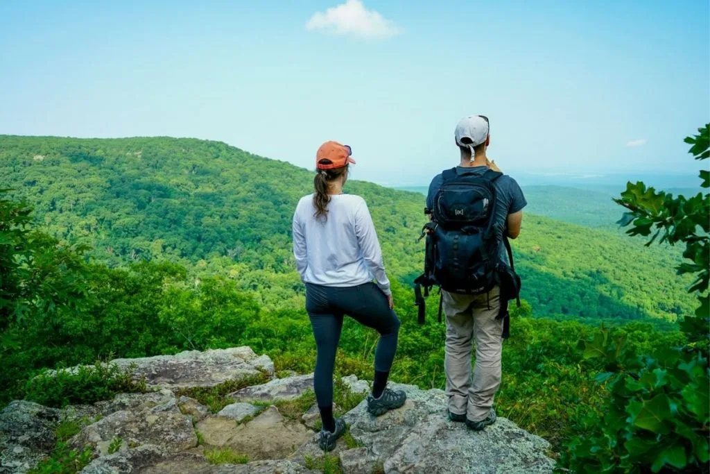 guide-on-what-to-wear-hiking Ashlee & Pablo hiking in the mountains, sunny day, green mountains, blue sky