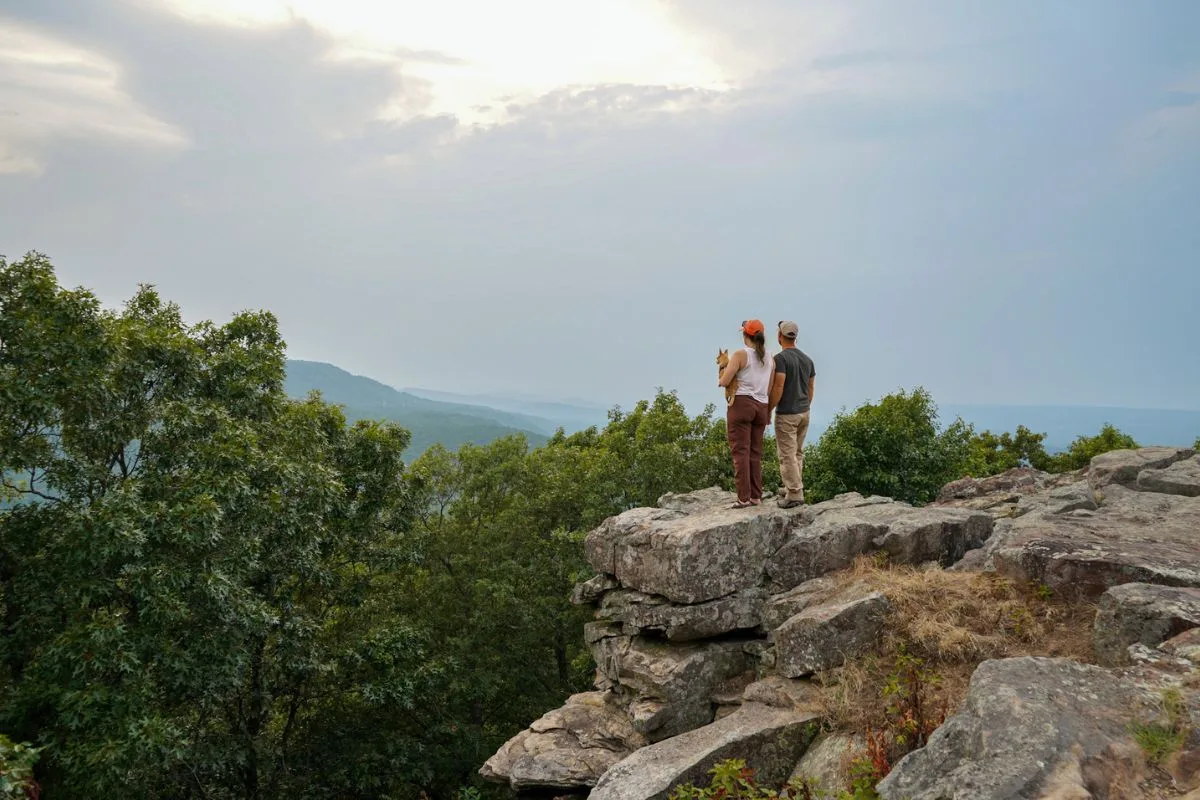 Ashlee and Pablo standing on the rocks overlooking a smoky sunset